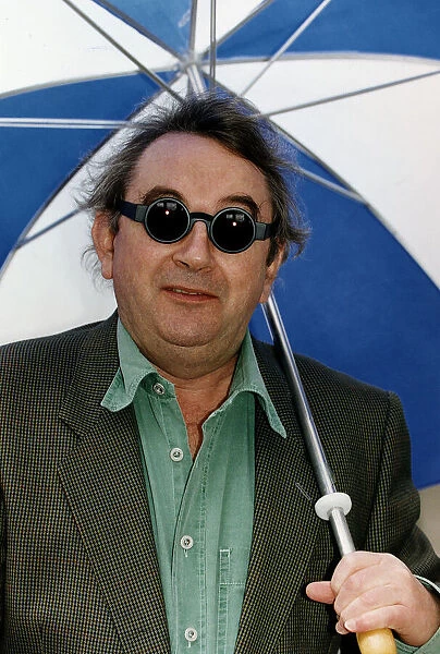 Ian McCaskill wearing a pair of Debenhams Mondo Sunglasses holding umbrella
