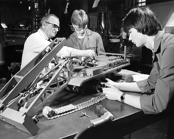 Instructor Jack Laybourn works on a model of an armoured bridgelayer with apprentices