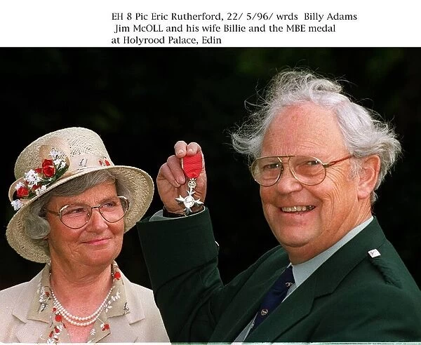 Jim McOll holding MBE medal at Holyrood Palace wife Billie looking