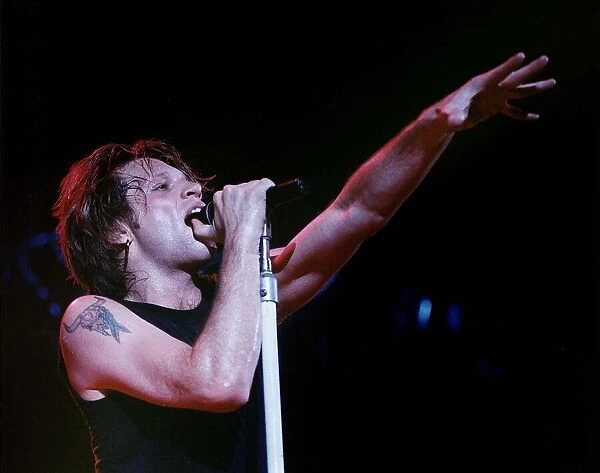 Jon Bon Jovi lead singer of rock group Bon Jovi raises his hand to the audience while