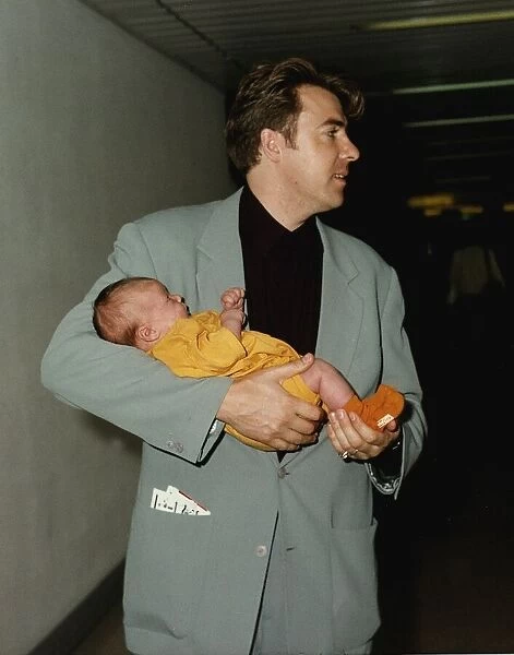 Jonathan Ross TV presenter holds baby in arms