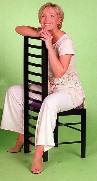 Kirsty Young TV Presenter Channel 5 sitting on chair wearing white trousers