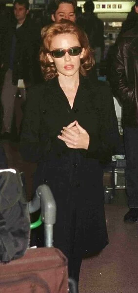 Kylie Minogue leaving Heathrow for Glasgow November 1997 hands clasped black coat