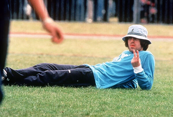 Liam Gallagherod pop group Oasis gives the v sign as hlies on the grass during a friendly