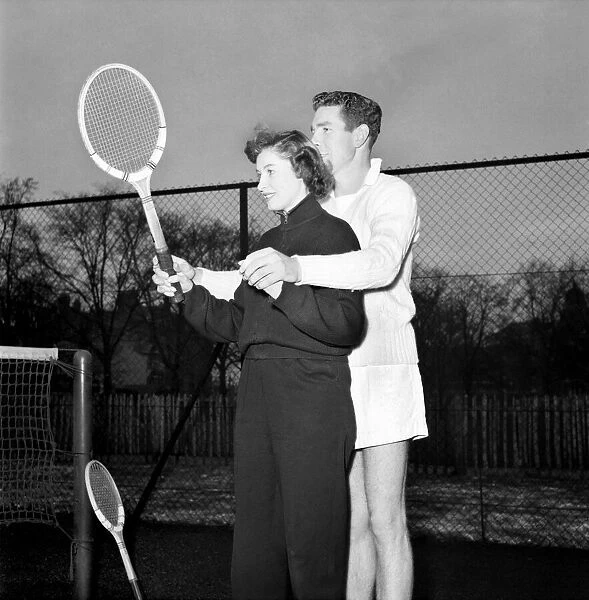 Man giving woman instruction on how to hold the tennis racket before a game