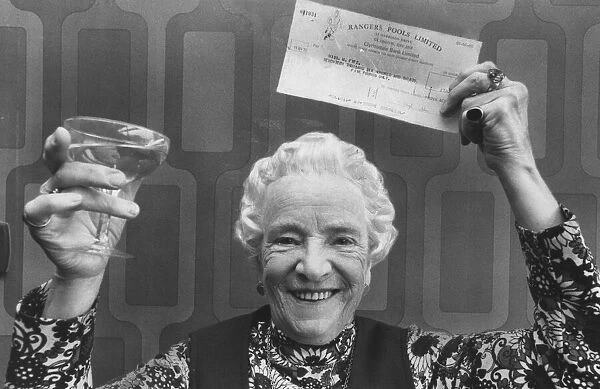 May Fyfe celebrates a pools win with a glass of champers, October 1976
