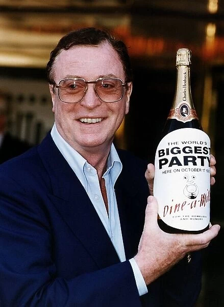 Michael Caine holding a large bottle of champagne