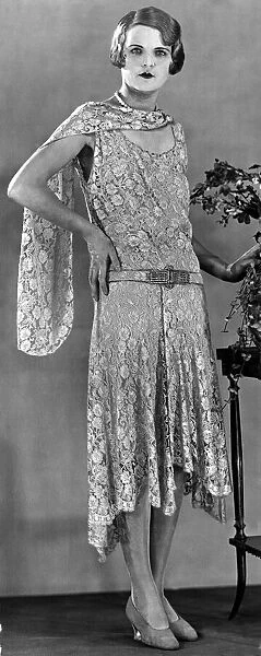 A model wearing a long patterned dress showing the popular uneven hemline in 1929