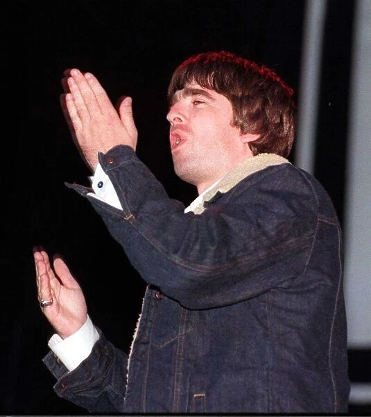 Noel Gallagher waving his hands in the air during a concert circa 1999