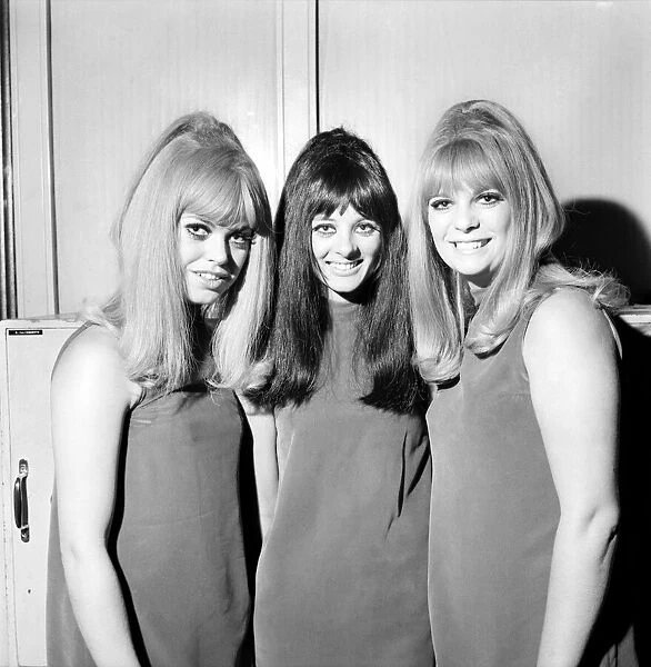 People Women: Three girls wearing mini dresses smile into the camera