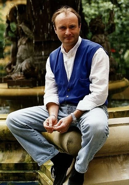 Phil Collins singer poses for a picture while sitting on the edge of a water fountain