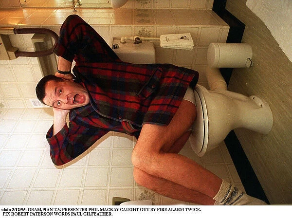 Phil MacKay Grampian TV Presenter with his hands over his ears sitting on toilet wc