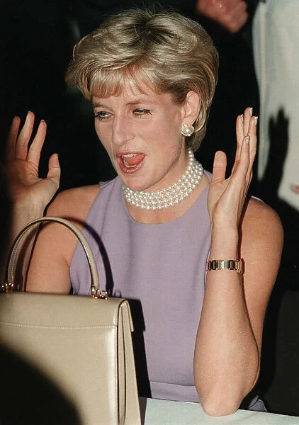 PRINCESS DIANA, WEARING A PURPLE DRESS AND NECKLACE LAUGHS AT AN EVENT HELD BY THE