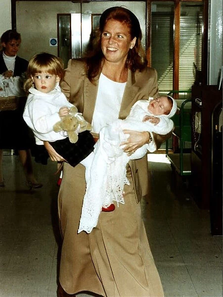 Princess Eugenie and Princess Beatrice being held by their mother the Duchess Of York at