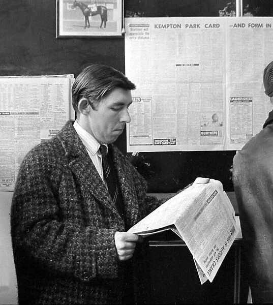 A punter checks the racing guide in a newspaper before making his bet at a race