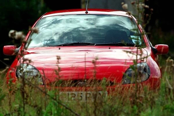 A RED FORD PUMA EXTERIOR PARKED IN GRASS AREA AUGUST 1997