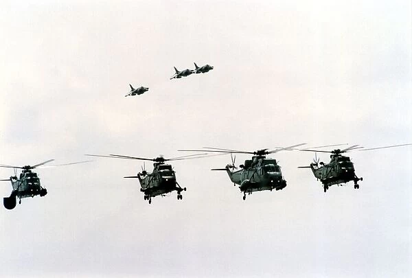 Four Royal Navy Sea King helicopters and three Sea Harriers in flight