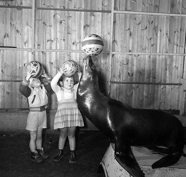 Two small children try to mimic the ball skills of one of Billy Smarts Circuses Sea Lion
