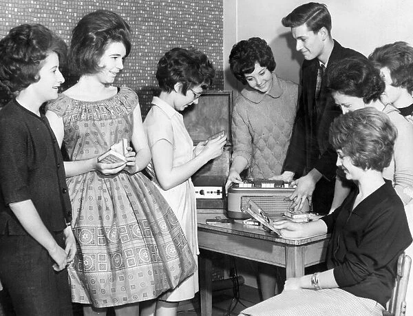 Teenagers crowd around the tape and record player at their local youth club