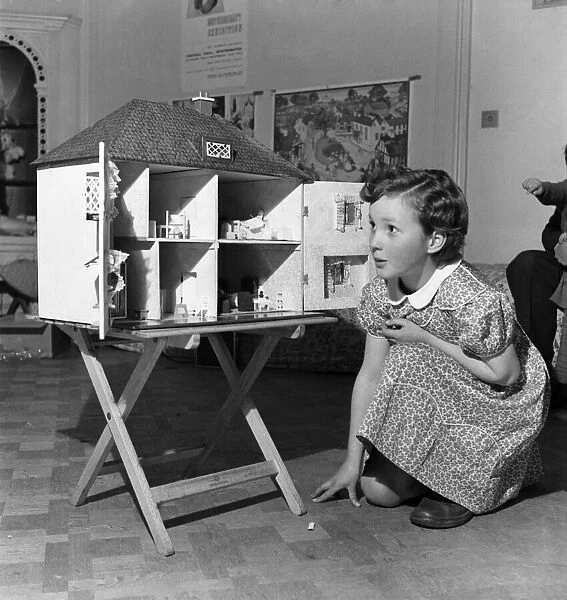 Young girl playing with dolls house. October 1952 C4969