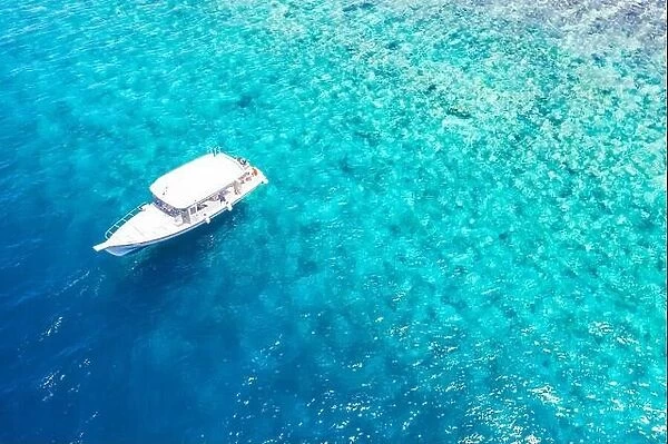 Beautiful turquoise ocean water boat top view aerial photo. Aerial view speed boat in the sea. Exotic sea lagoon, snorkel adventure, tropical ocean
