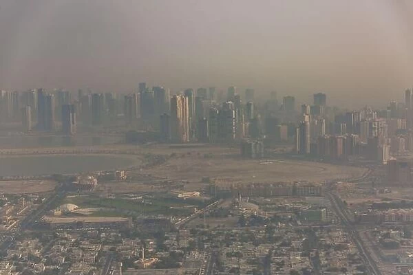 DUBAI, UAE - APRIL 29: Aerial view of Downtown Dubai and skyscrapers during morning sandstorm. Highway and trainline, soft light over the sand