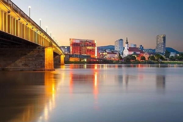 Linz, Austria. Cityscape image of riverside Linz, Austria at summer sunset with reflection of the city lights in Danube river