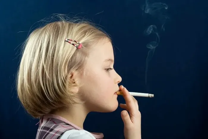 little girls smoking cigarettes Cigarette. Poor blue-eyed girl holding a cigarette and while her parents working on their laptops Stock-bilde Portrait of a small girl
