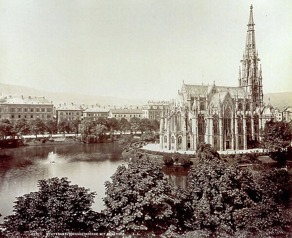 The apse and left side of the gothic Johanniskirche (church of St. John) in Stuttgart, surrounded by a lake. In the foreground a few trees