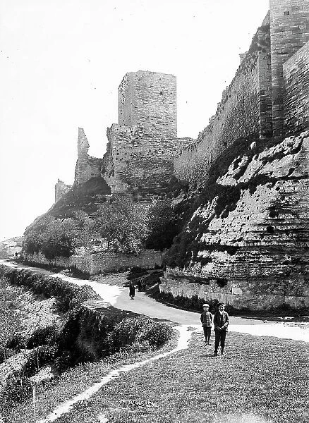 Two boys along a country road under ancient walls, Castrogiovanni (today Enna)