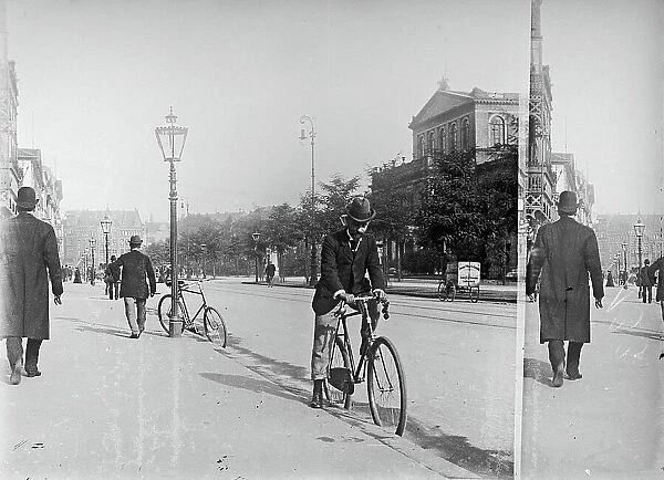 Busy view of a street in a German city. In the foreground a man on a bicycle