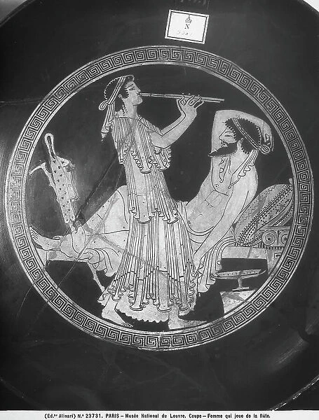 Detail of the central medallion inside an Attic red-figure cup, depicting a woman playing the flute and a reclining man, resting; in the Louvre Museum, Paris