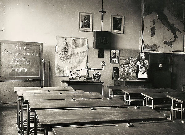Elementary schools Giovanni Berta, Lecco: a classroom with some teaching aids; on the blackboard the words 'Duce we will bring the Fascist School on the Plan of the Empire'