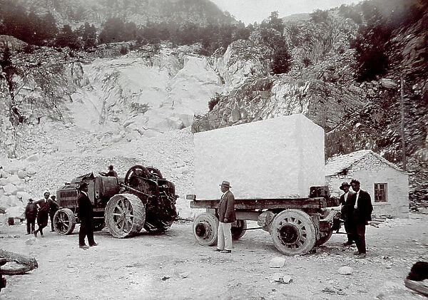 Extracting marble from a quarry. A block of marble is being transported on a tractor with several workers around