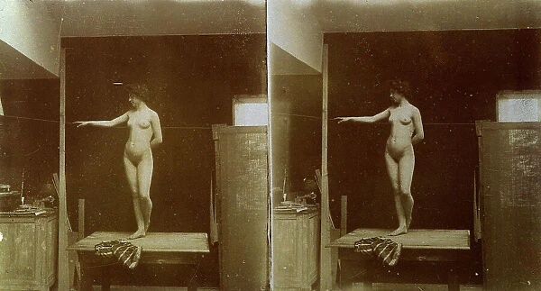 Female nude: the model is posing standing on a table, with her legs crossed, one arm is hanging at her side with the other behind her back