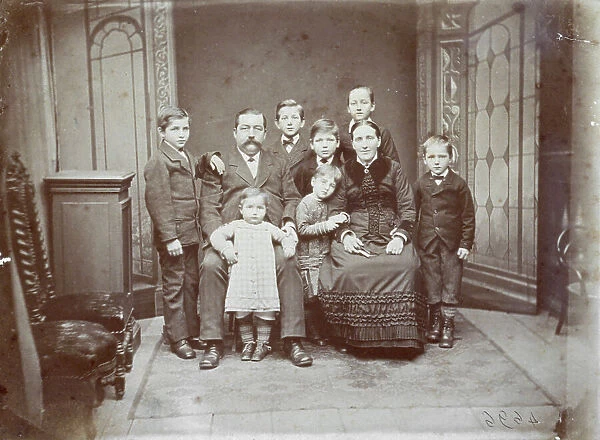 Full-length portrait of a family group composed of a couple, seated, surrounded by their seven children. They are all elegantly dressed. The lady's dress is edged in velvet