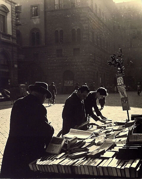 Three men consulting books on sale on a bench in Strozzi's Square, Florence
