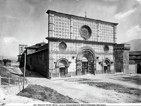 View of the Church of S. Maria di Collemaggio near L'Aquila. The Romanesque faade is covered in white and red marble; the lower part has three doors with restored splayed arches; the upper part has three open rose windows. A bell gable is visible in the background