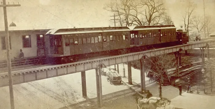 Framed Print : View of an elevated railway structure with train that has pulled into the station, in New York city. In the street below some freight wagons are parked Framed Print : View of an elevated railway structure with train that has pulled into the station, in New York city. In the street below some freight wagons are parked
