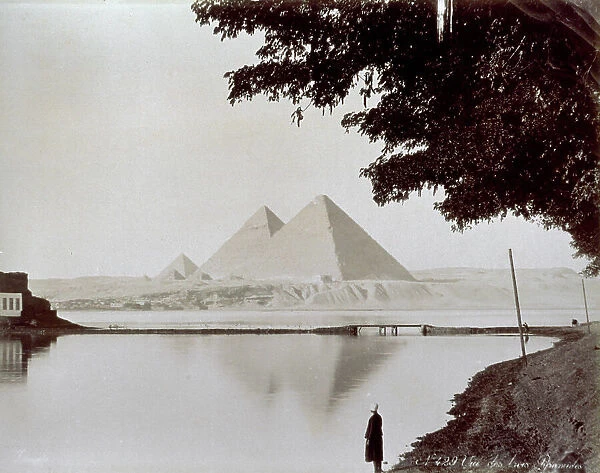 View of the three great pyramids of Khufu (Cheops), Khafre (Chefren) and Menkaure (Mycerinus) in the necropolis of Giza. In the foreground, a stretch of the Nile