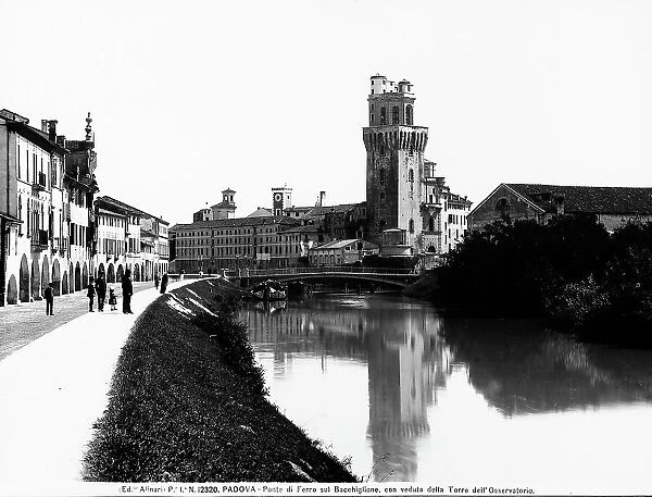 View of the Tower of the Observatory and the iron bridge over Bacchiglione in Padua. On the left, some passersby are visible