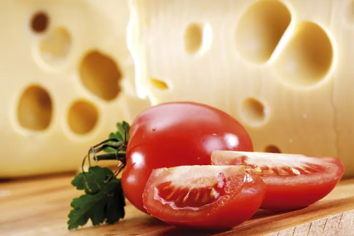 Framed Print : Whole and cut tomatoes in front of cheese Print