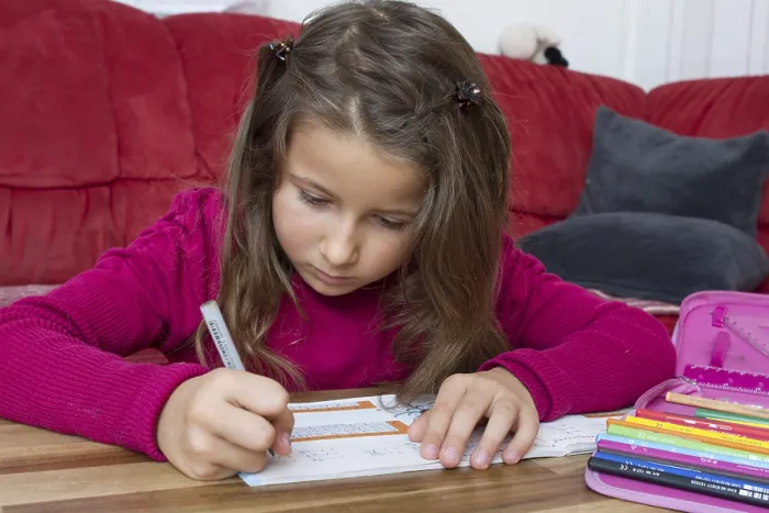 Framed Print : Seven-year-old girl completes homework on sofa Framed Print : Seven-year-old girl completes homework on sofa