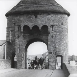 Monnow Bridge Print, a photograph of a man leading a horse and cart through the Monnow Gate