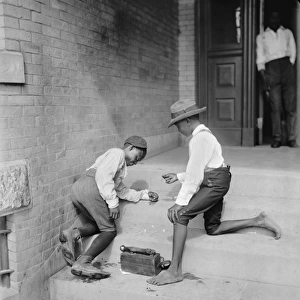 Two African American shoe shine boys playing a gambling game