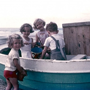 Four children on a beach, playing with a boat