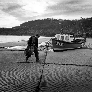 Fisherman walks up the beach - New Quay, Wales