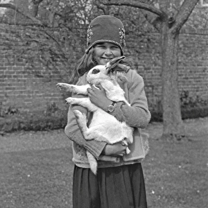 Girl holding rabbit in a garden