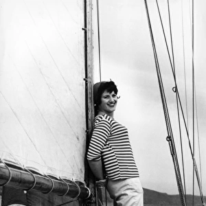 Girl in striped shirt leaning on the mast of a sailing boat
