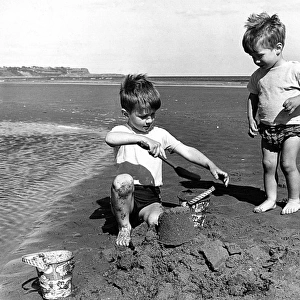 Two little boys making sandcastle on beach
